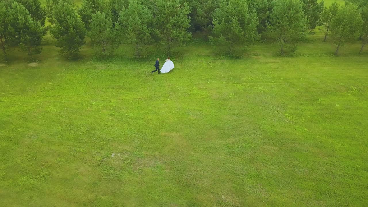 신랑은 필드 안테나에서 긴 드레스를 입고 신부를 따라 달린다.