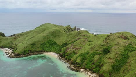 green meadow hills on overcast day at bukit merese lombok surrounded by tropical ocean, aerial