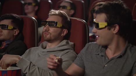 friends eating popcorn in movie theater. people watching movie in 3d glasses