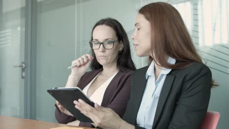 mujeres de negocios exitosas sentadas juntas y viendo en la tableta