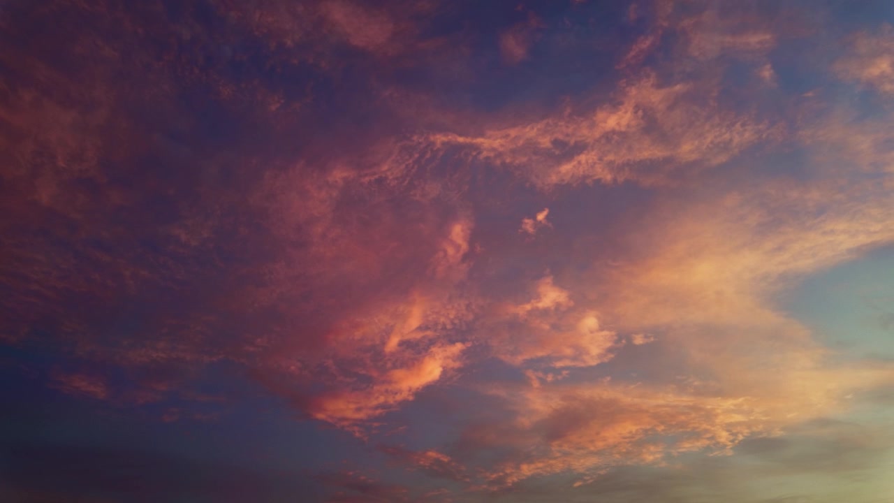 Looking Up At Dramatic Cloudscape During Sunset With Warm Orange And Pink Hues. low angle, panning shot