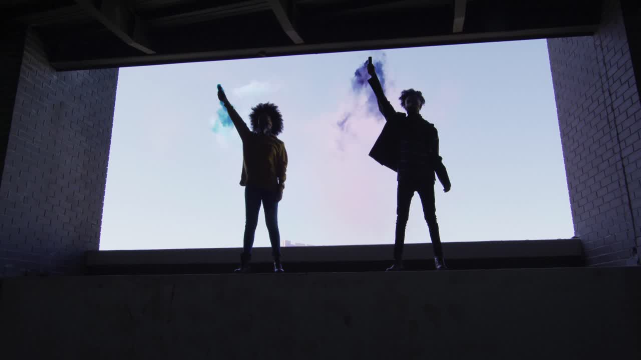 혼성 인종의 남성과 여성이 빈 건물에 서서 파란색과 보라색  ⁇ 불을 들고 있습니다.