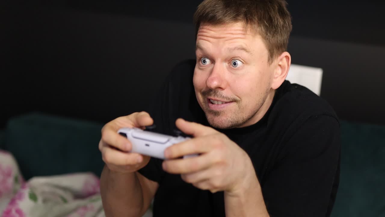 Man showing various intense emotions while playing video games with a controller