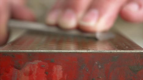 una foto macro de enfoque en rack de un cincel que un carpintero está afilando en una piedra de afilar