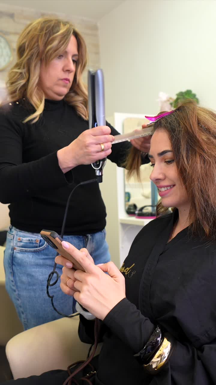 Hairdresser Straightening a Woman's Hair in a Beauty Salon