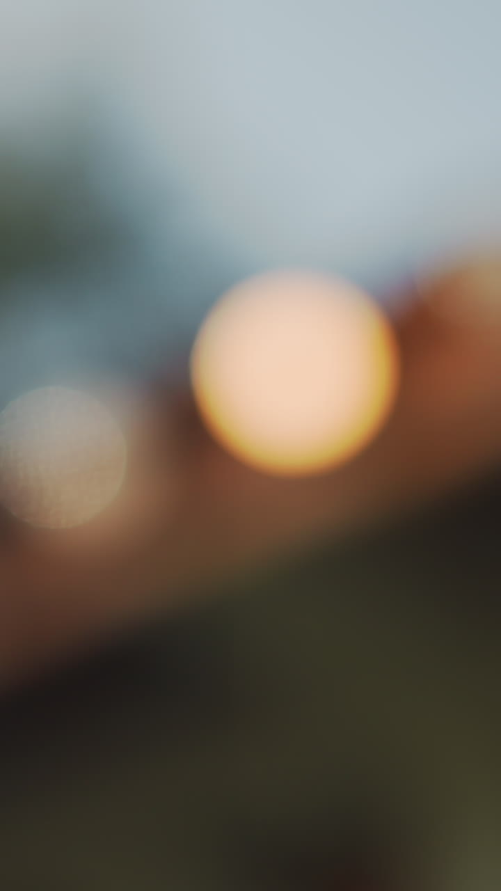 luces bokeh suaves sobre tejas, composición abstracta onírica y desenfocada con esferas doradas cálidas, ambiente crepuscular, vegetación de fondo difuminada, ambiente romántico de festival y boda, mood board de diseñador