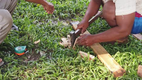slow motion shot of a men shaving a small piece of wood with axe