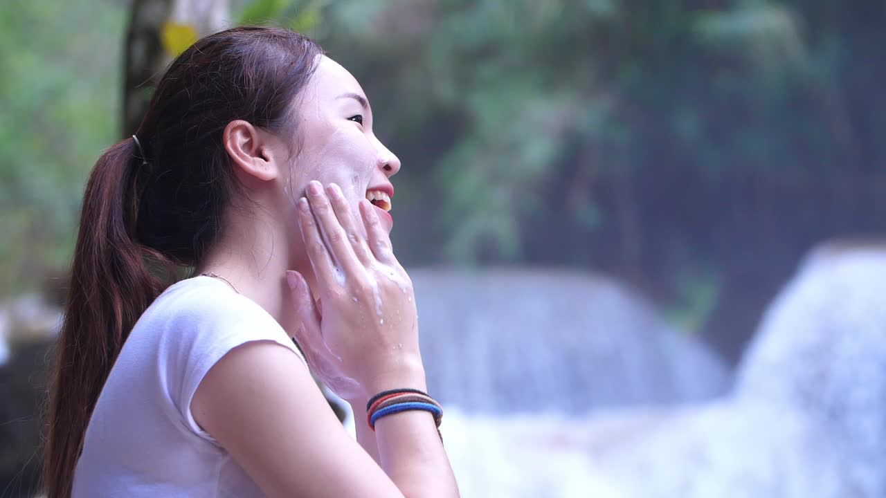 Woman Happy Cleanses The Skin With Foam Near Waterfall