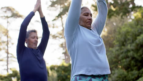 focused diverse senior couple practicing yoga meditation in sunny garden, copy space