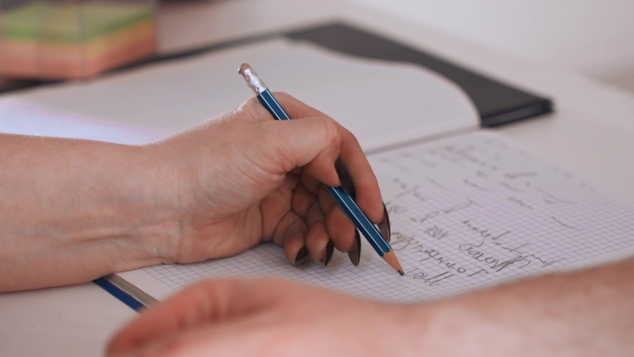 Paramedico di colore che scrive appunti del paziente durante una visita domiciliare, primo piano della mano che tiene una penna blu su cartella clinica e blocco note, scrittura concentrata, documenti e dettagli della valutazione, professionista calmo