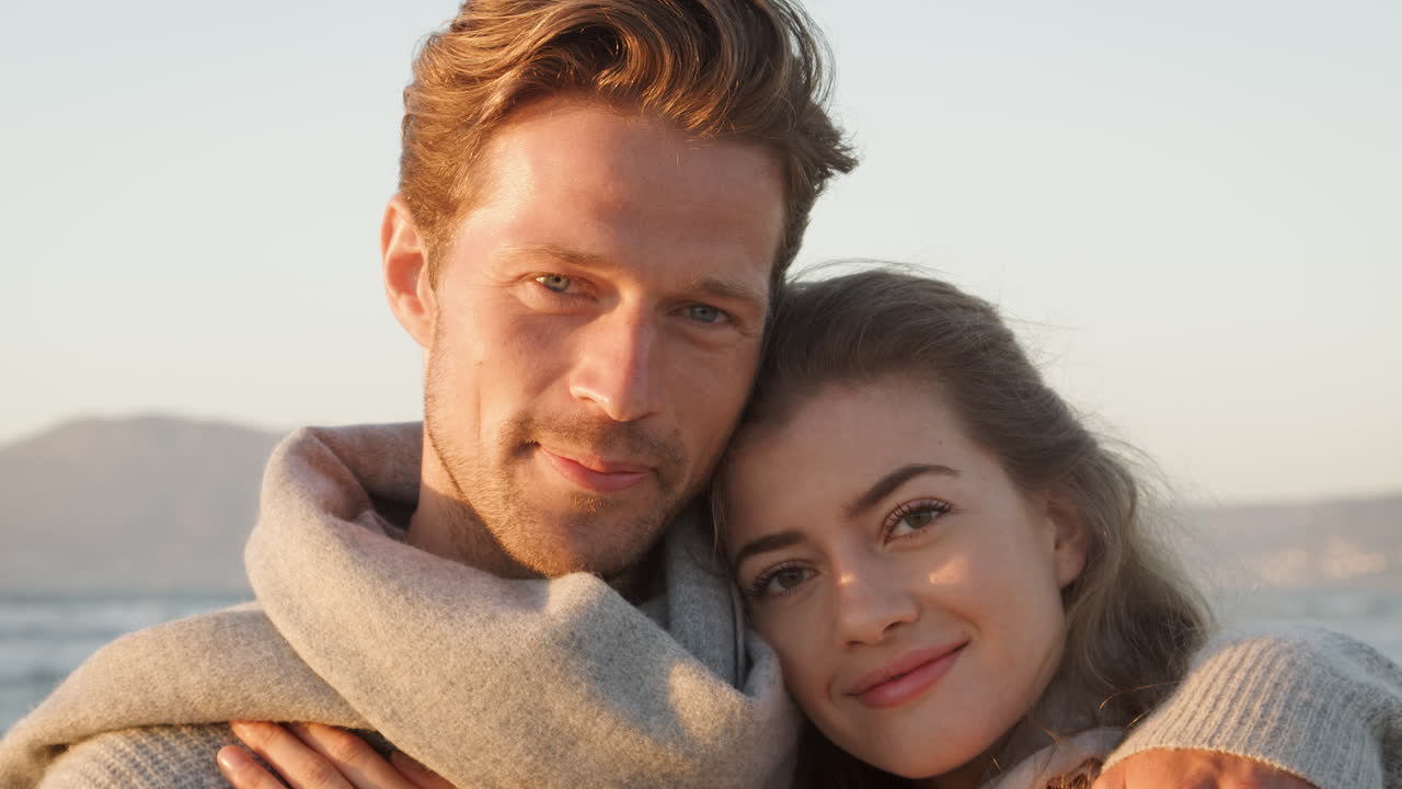 Portret van verliefd stel dat samen langs een winterstrand wandelt.