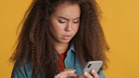 Sad Caucasian curly haired woman scrolling on smartphone.
