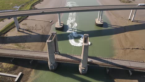 view of kingsferry bridge and sheppy crossing with jet skiers cruising on the swale river in the uk on a sunny day