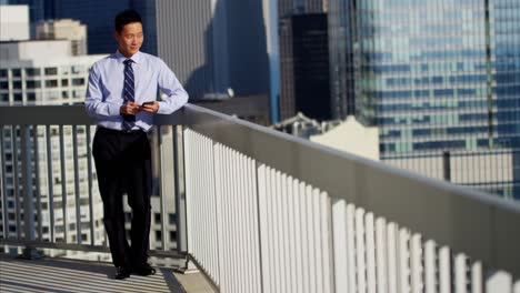 asian businessman working on rooftop using mobile technology