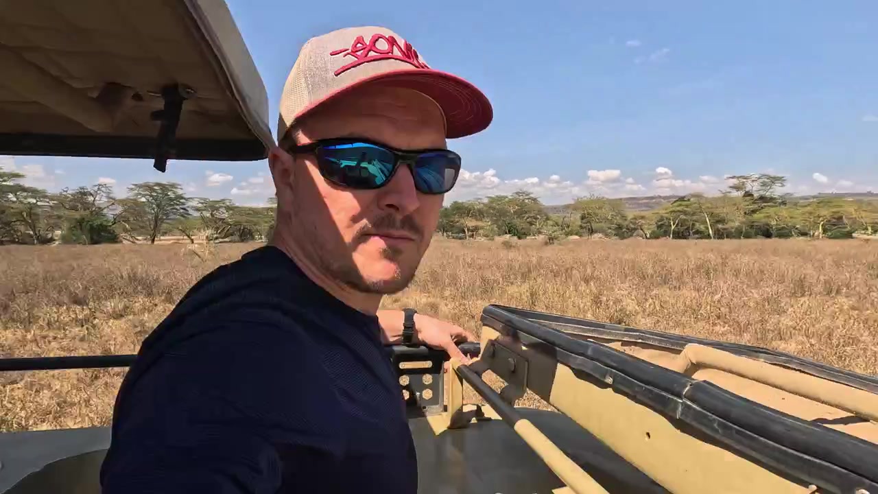 Sideprofil af turist, der kigger fra safaribilens tag i Kenyas savanne