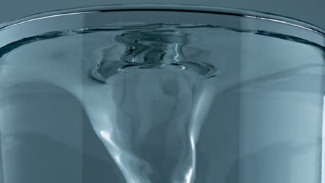 mineral drink spinning transparent cylinder closeup. pure water vortex glass