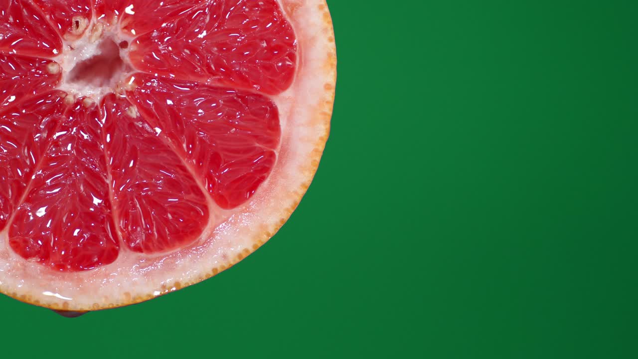 Dalle fette di pompelmo rosso maturo gocciola una goccia di succo