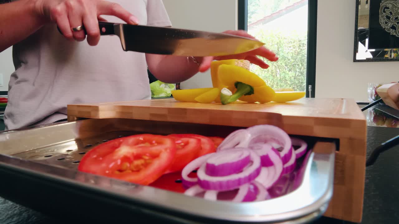 los pimientos se cortan en una tabla para cortar con otras verduras como el tomate o la cebolla con una tableta encima