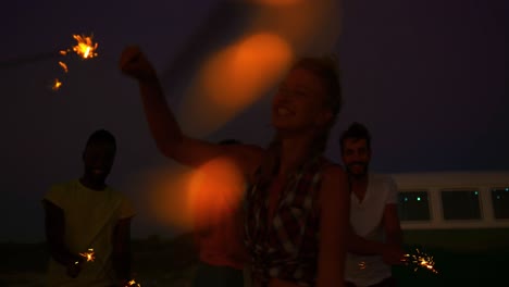 young adult friends having fun on the beach at night with sparklers 4k