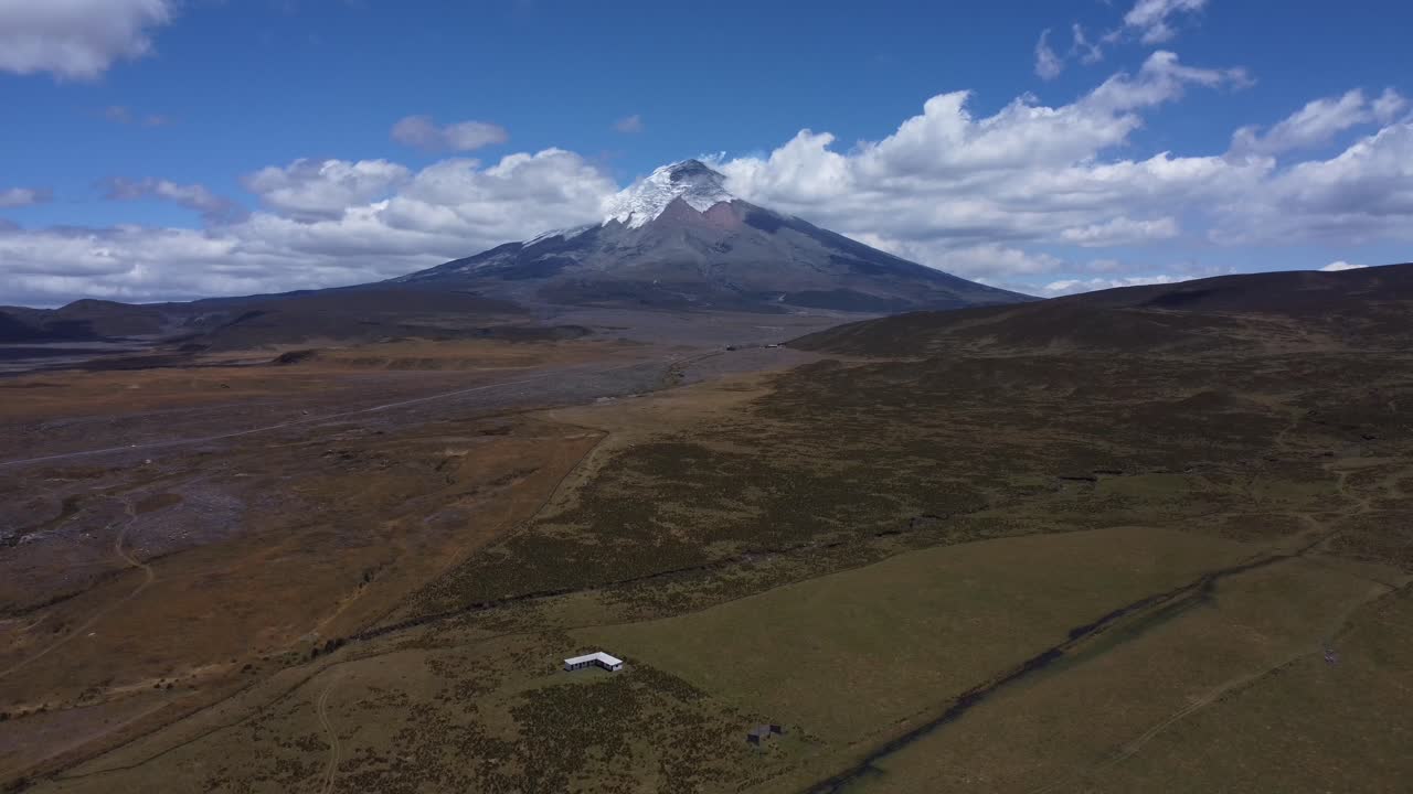 presenciar el impresionante volcán cotopaxi en 4k mientras nuestro avión no tripulado se retira con gracia, capturando la belleza serena del majestuoso pico contra un telón de fondo de cielos azules claros y suaves nubes circundantes
