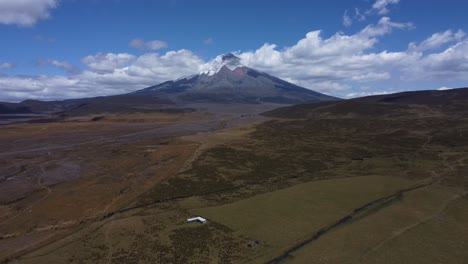 Sea-Testigo-Del-Impresionante-Volcán-Cotopaxi-En-4k-Mientras-Nuestro-Dron-Se-Retira-Con-Gracia,-Capturando-La-Serena-Belleza-Del-Majestuoso-Pico-Con-Un-Telón-De-Fondo-De-Cielos-Azules-Claros-Y-Suaves-Nubes-Circundantes.