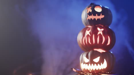 video of halloween carved pumpkins and smoke with copy space on blue background