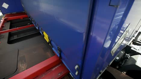 a blue cargo container being loaded onto a red platform in an industrial setting