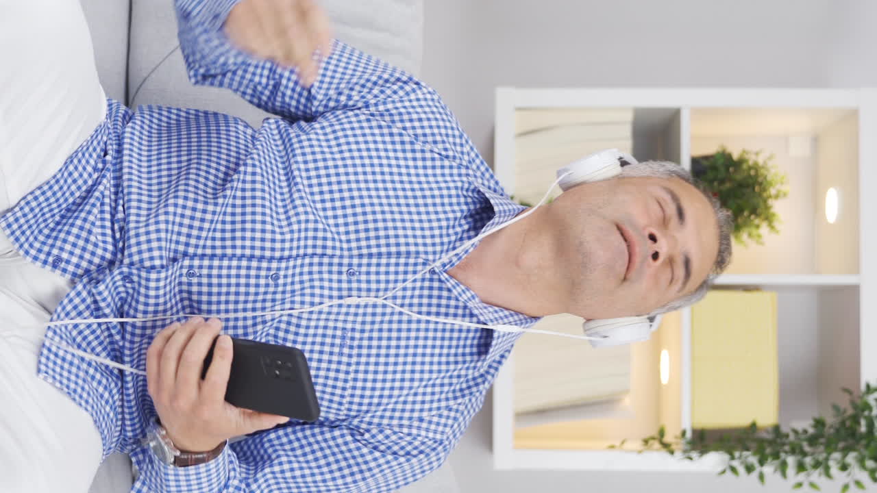 헤드폰으로 음악을 듣는 행복한 남자의 수직 비디오.