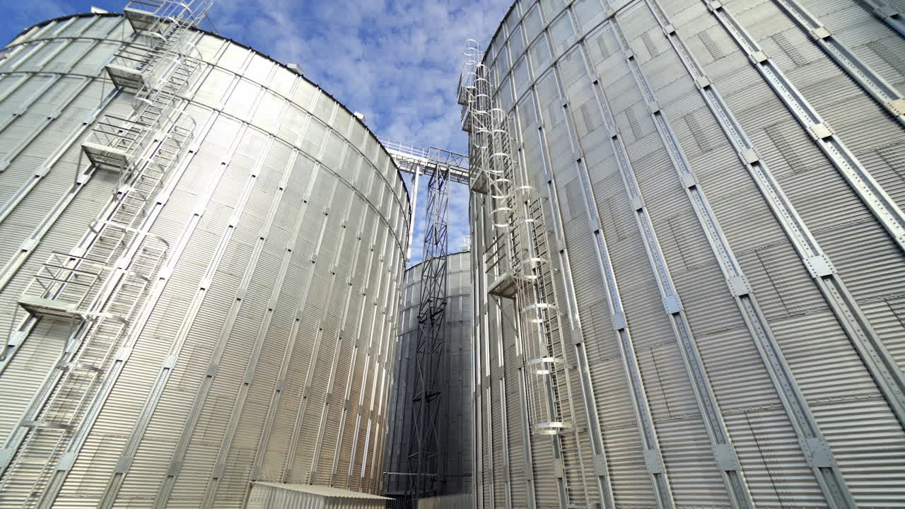 Aluminum grain elevators. Agricultural equipment for storing harvest. Modern warehouse. Granary in a sunny day. Close-up.