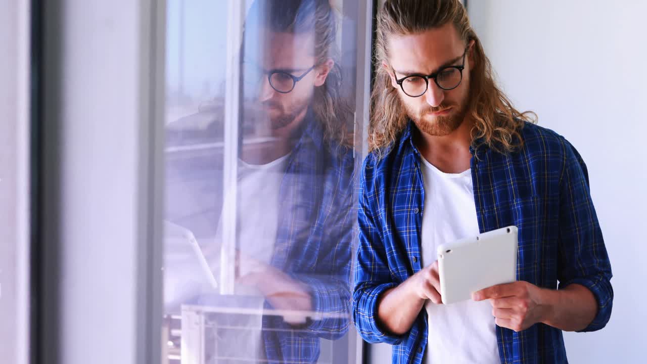 ejecutivo masculino usando tableta digital cerca de la ventana