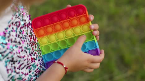 niña jugando coloridas burbujas de silicona suave juguete sensorial simple hoyo pop juego, primer plano