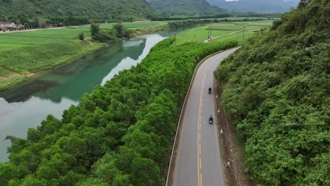 Toma-Aérea-De-Un-Dron-De-Una-Carretera-Que-Pasa-Por-Colinas-Y-Un-Río-En-El-Costado