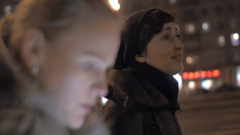 women having friendly talk during evening walk in the city