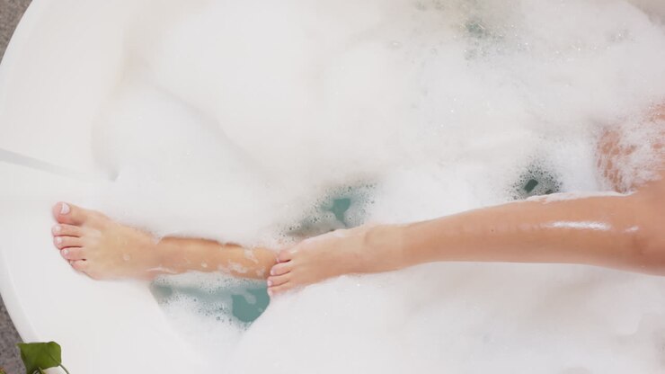 Rilassarsi nella vasca da bagno, donna che si gode un bagno schiuma con schiuma e acqua
