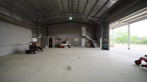 spacious industrial style shed interior with high ceilings, concrete floors, and large open space with off road capable vehicle and lawn mower
