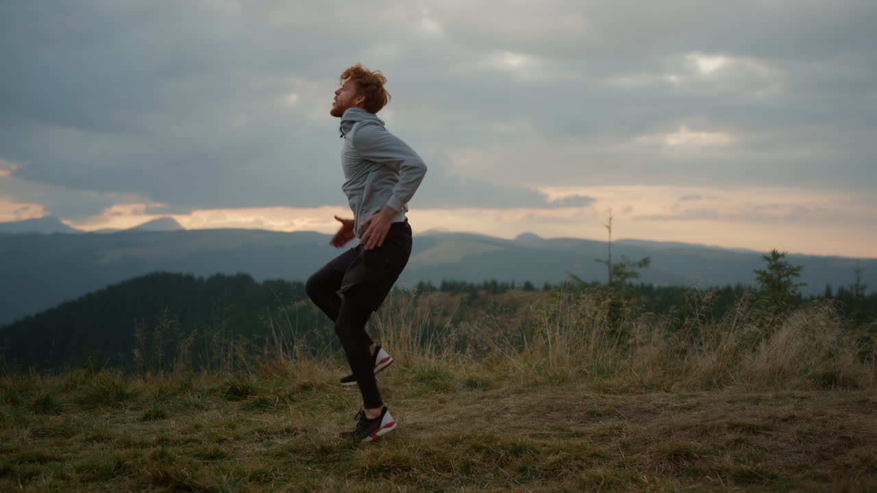 Uomo che esegue gli high knee taps durante l'allenamento fitness. Ragazzo che si allena in montagna.