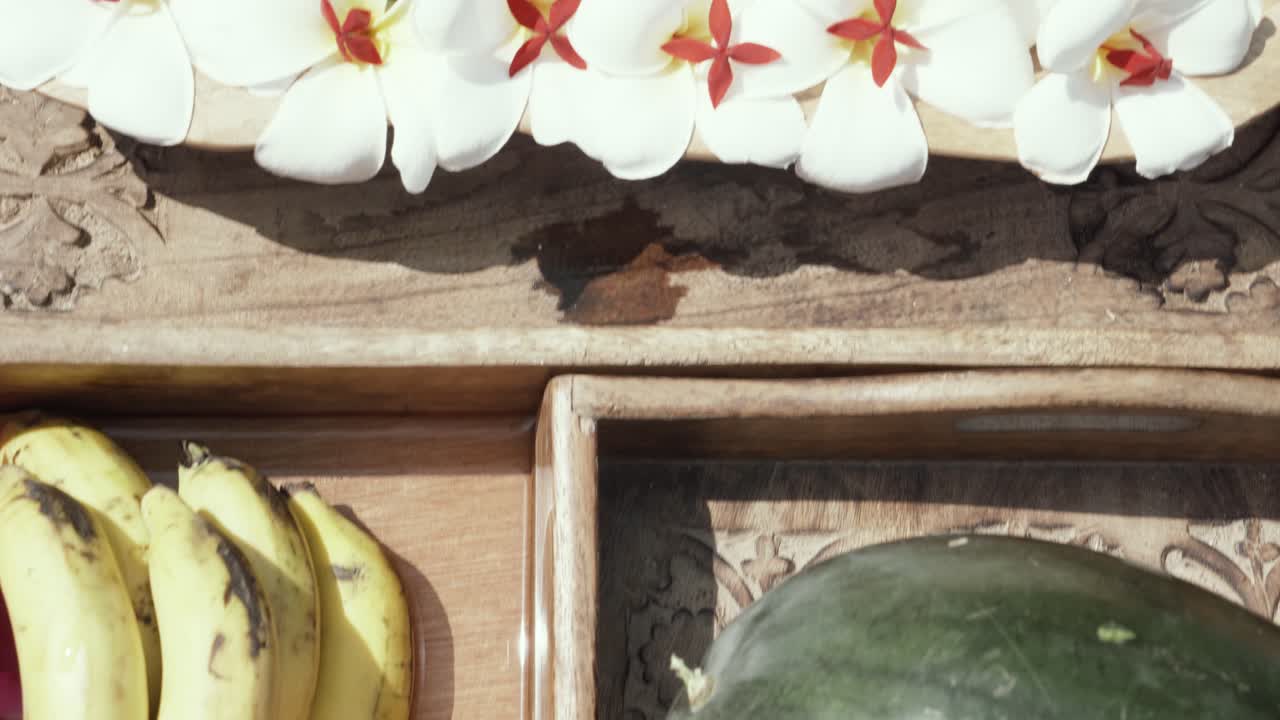 흰색과 보라색 꽃, 바나나, 수박, 주스 한 잔, 인도 수영장의 고아 리조트에 있는 이국적인 과일 나무 접시