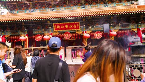 people praying and offering incense at temple