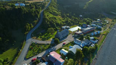 Luftdrohne-Fliegt-über-Die-UNESCO-Patrimonialkirche,-Die-Chilenische-Patagonien-Landschaft-Von-Detif-Chiloé-Mit-Skyline,-Grünen-Inselbergen,-Häusern-Und-Südamerikanischer-Straßenfahrt