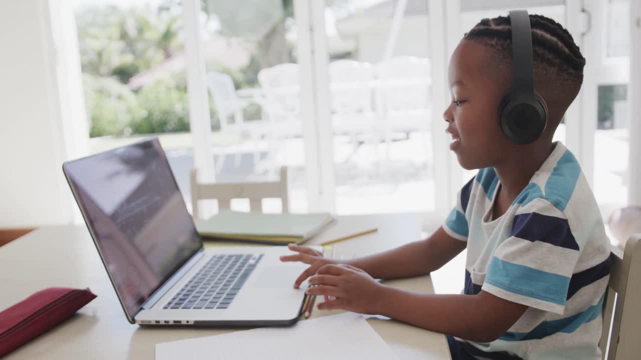 African american boy using laptop for online lesson, in slow motion