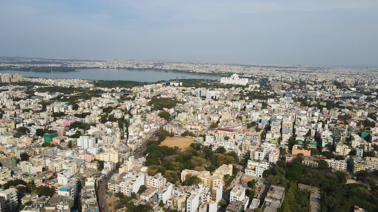 Aerial drone shot offering a sweeping view of Hyderabad’s metropolitan area, revealing a dense network of roads, flyovers, and high-rise buildings.
