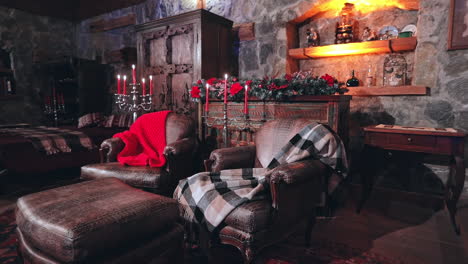 empty comfortable living-room with christmas decorations. warm blankets on soft armchairs and candlesticks with red candles in the house.