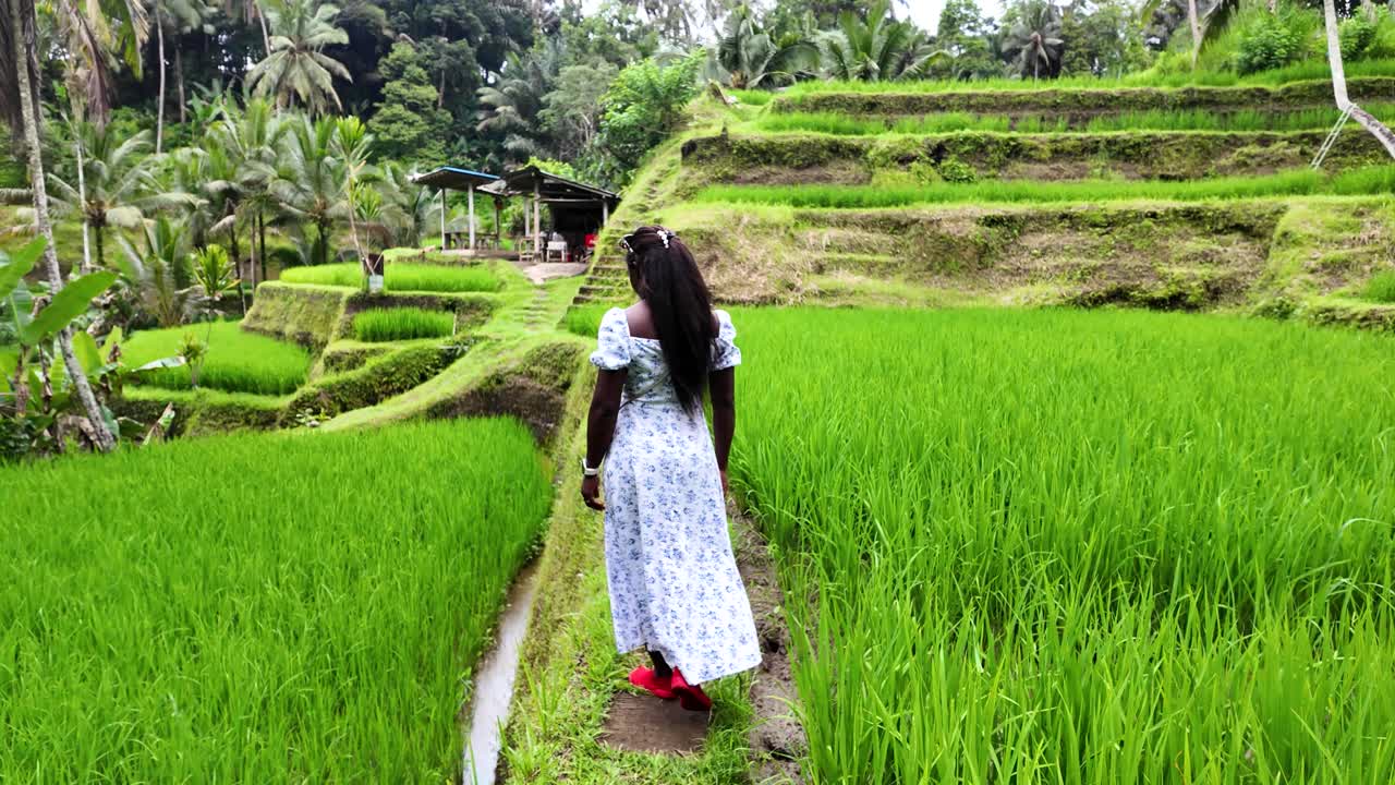 Woman walks through lush Bali rice terraces feeling peaceful outdoors