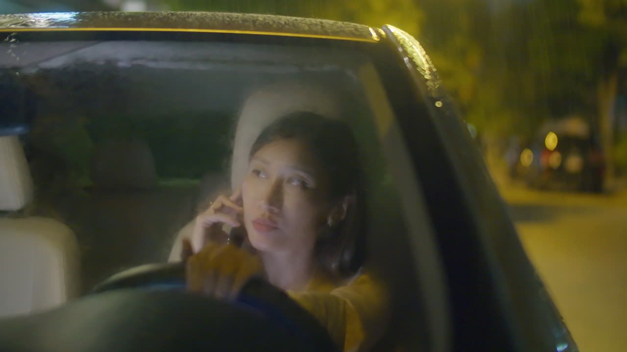 Asian Business Lady Speaking on Phone in Car at Rainy Night