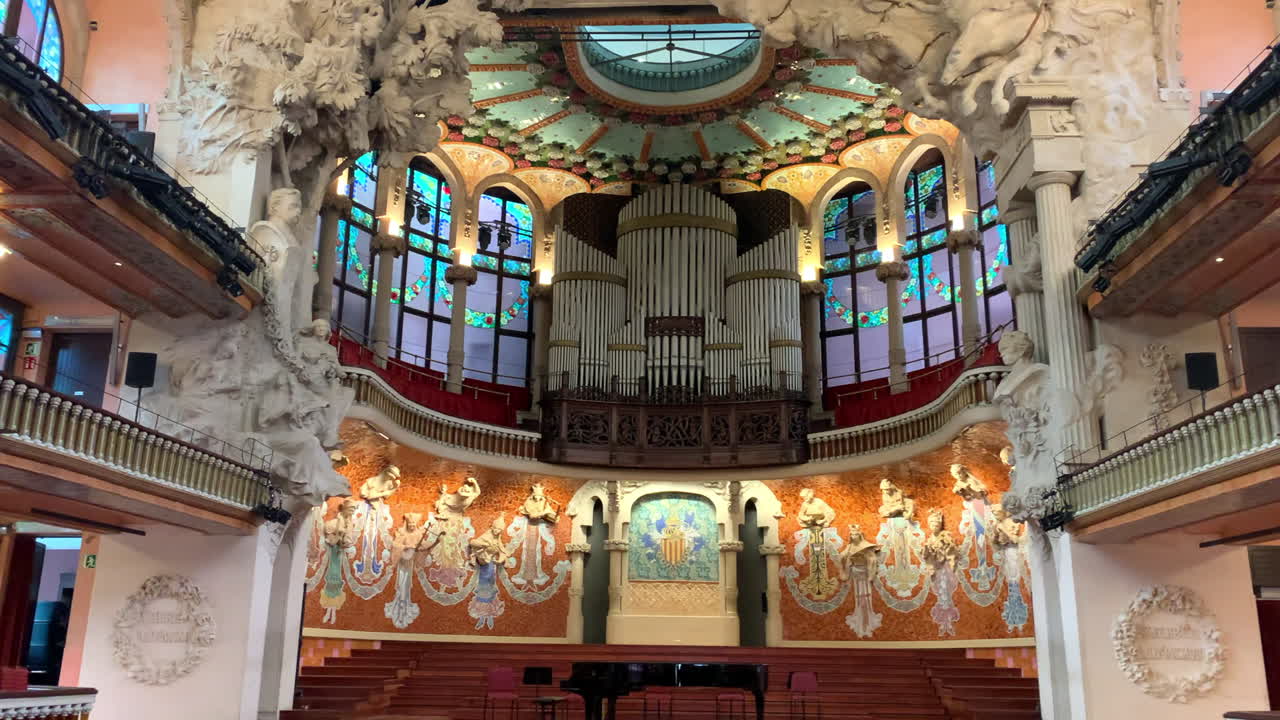 Il Palazzo della Musica Catalana, Palau de la Música Catalana, è un gioiello architettonico del modernismo e l'interno è visivamente mozzafiato. Lenta panoramica che inizia da sinistra del palco con un pianoforte a coda.