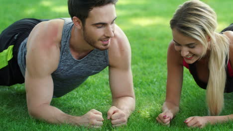 Fitness-couple-training-plank-workout-giving-five-after-finish-in-summer-park