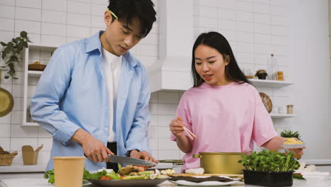 pareja japonesa cocinando comida japonesa mientras hablan y se ríen en la cocina 1