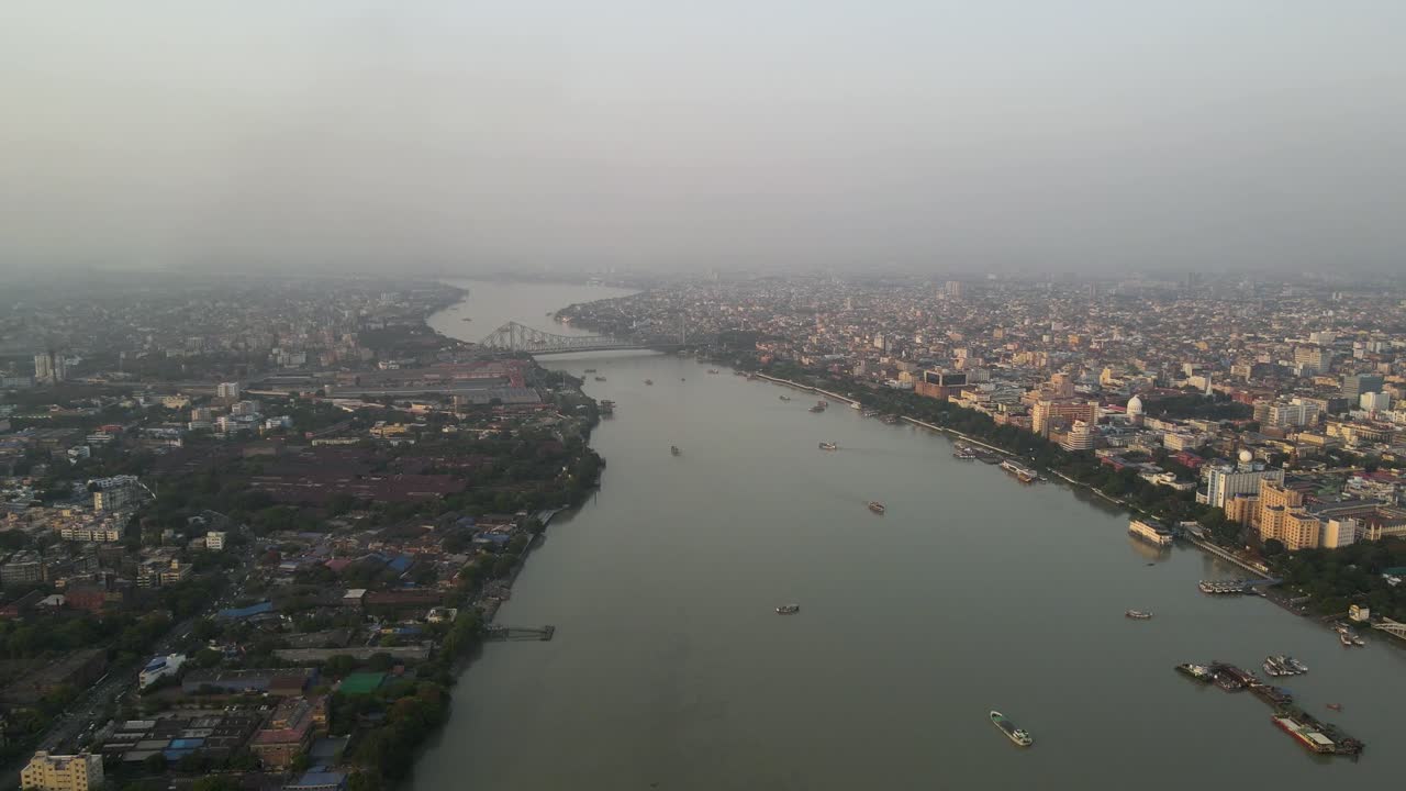 Aerial drone shot of Howrah Bridge spanning the Hooghly River, a landmark of Kolkata's rich heritage.