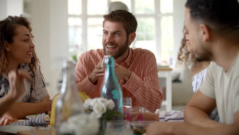 young adult friends sit talking around a dining room table