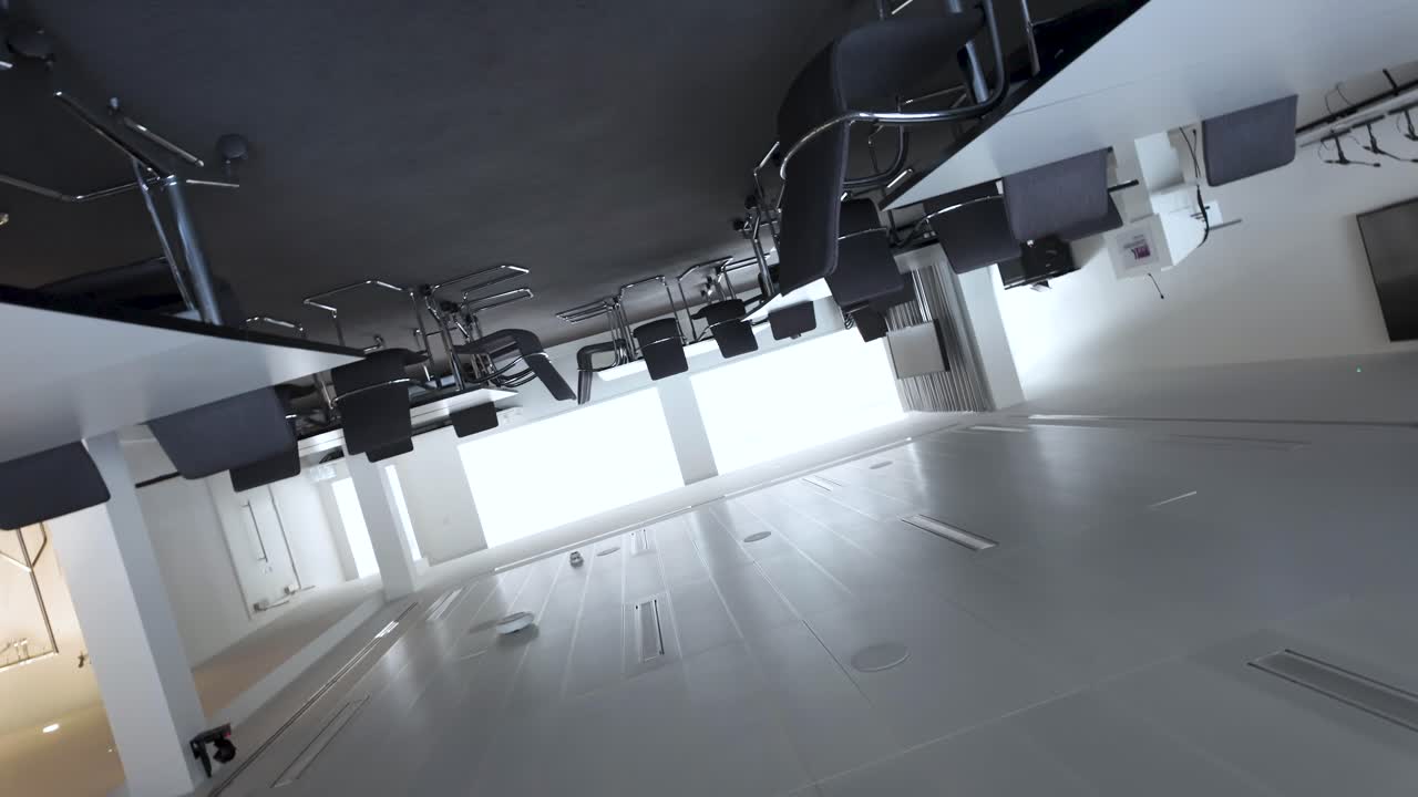 빈 회의실 또는 회의실의 회전 관점, 의자 및 테이블로 장착되어 있으며, 전문적인 분위기와 기업 설정 내의 협업 전망을 보여줍니다.